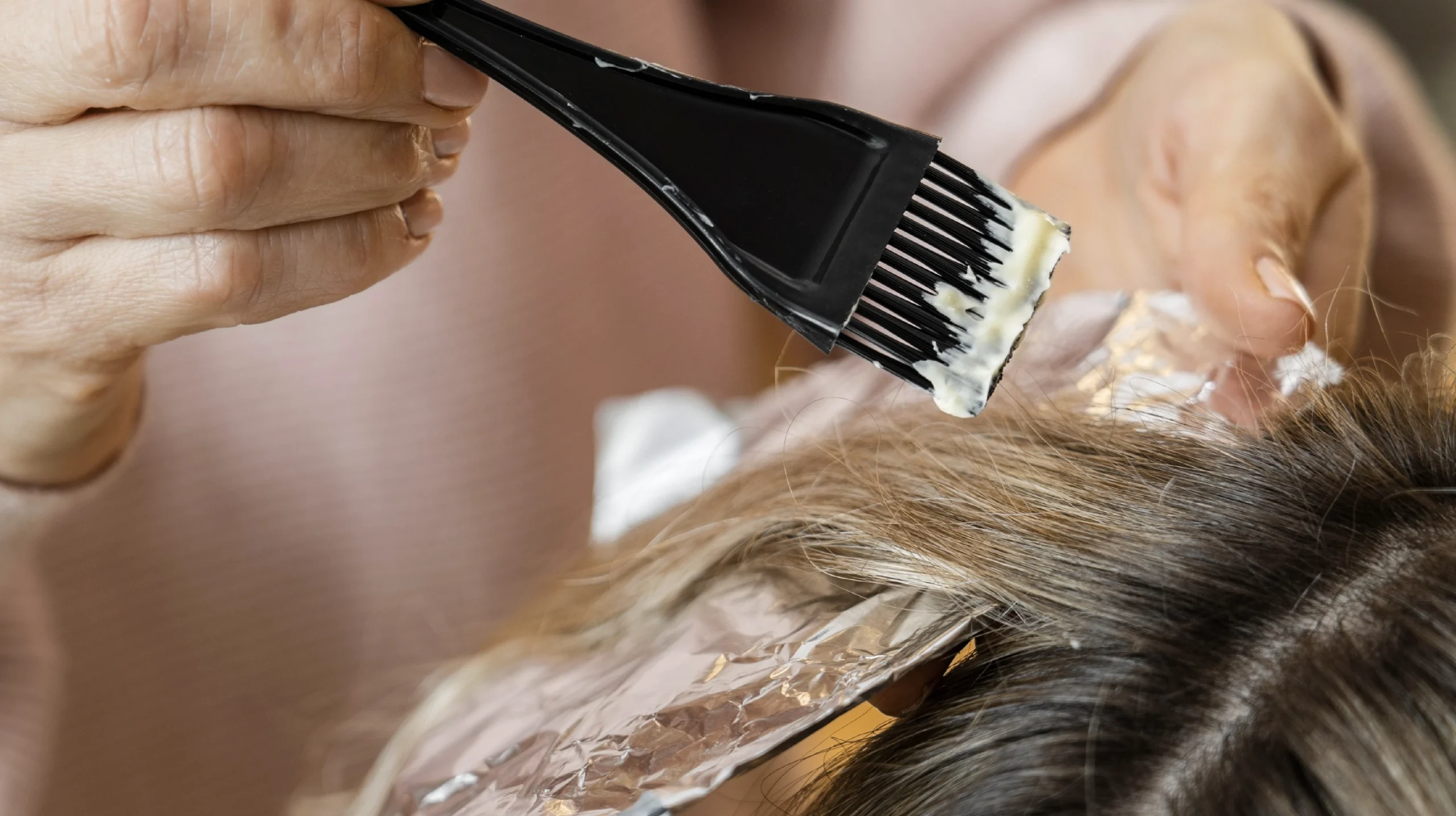 Hair color being applied with a brush and foil during an essential-level coloring technique