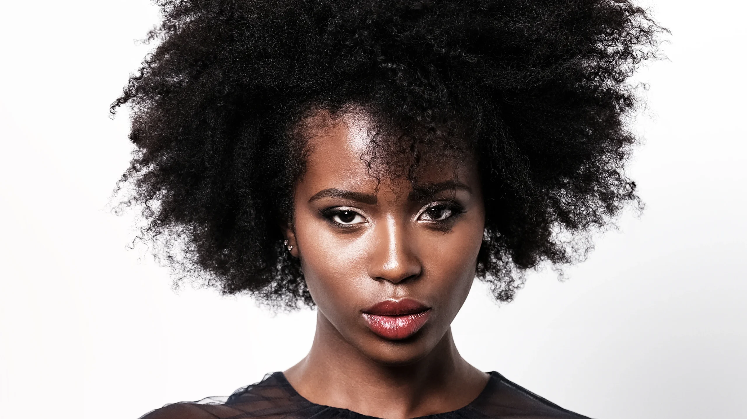 Model with natural afro-textured curls showcasing volume and definition against a clean background