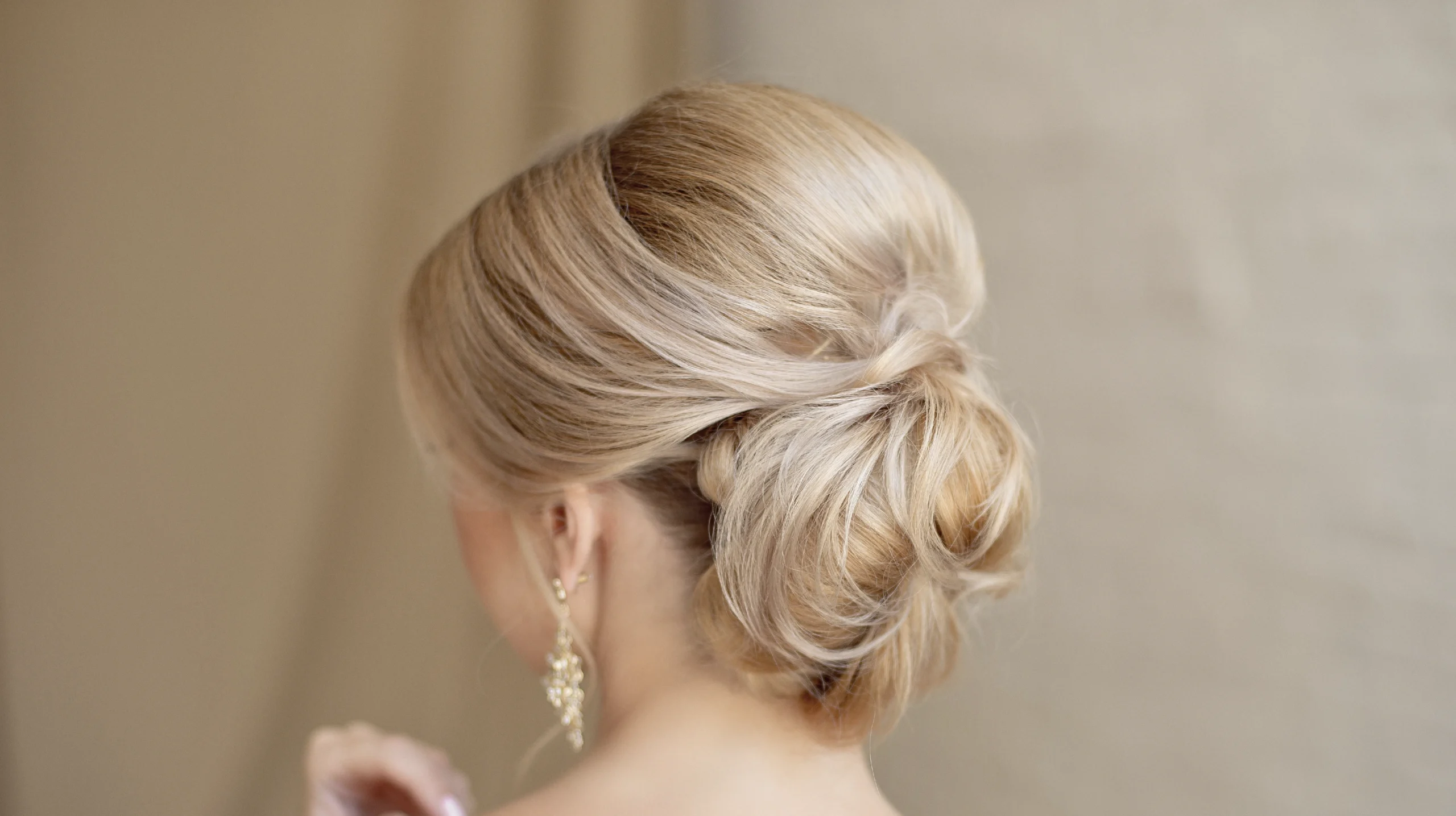 Elegant modern updo hairstyle with a softly textured low bun and smooth blonde hair